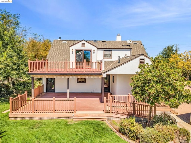 back of property with a deck and a lawn