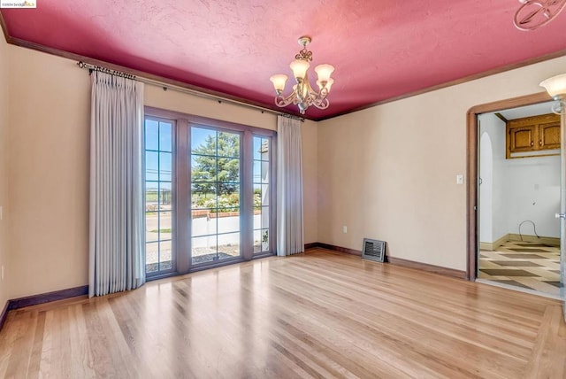 empty room featuring a textured ceiling, light hardwood / wood-style floors, and a chandelier