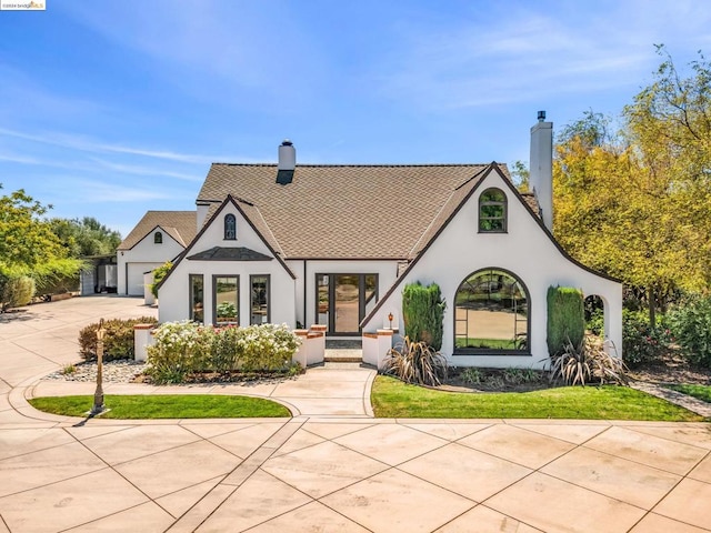 tudor house with a garage and a front lawn