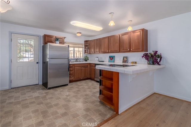 kitchen with pendant lighting, a wealth of natural light, tile counters, and appliances with stainless steel finishes