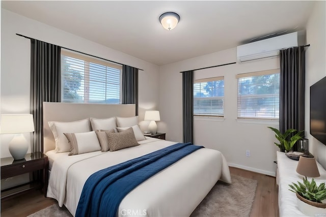 bedroom featuring wood-type flooring, a wall mounted air conditioner, and multiple windows