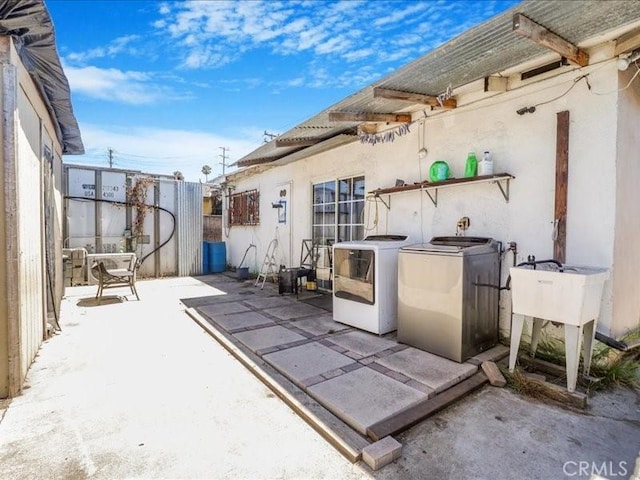 view of patio featuring washing machine and clothes dryer and sink