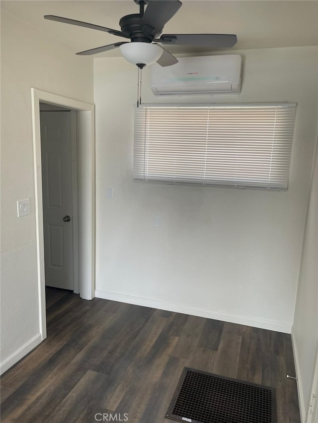 spare room with dark wood-type flooring, a wall unit AC, and ceiling fan