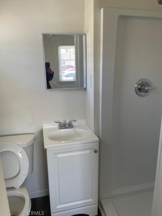 bathroom with toilet, walk in shower, and vanity