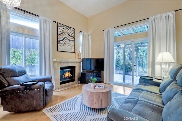 living room featuring light hardwood / wood-style floors, an inviting chandelier, a premium fireplace, and a wealth of natural light