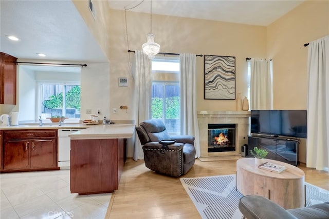 kitchen with a high end fireplace, decorative light fixtures, a chandelier, dishwasher, and light wood-type flooring