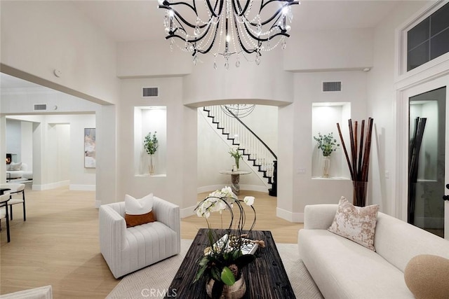 living room with light hardwood / wood-style flooring, a high ceiling, and a notable chandelier