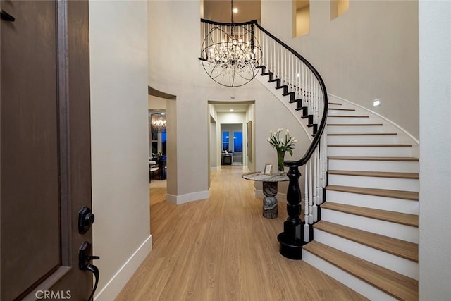 foyer featuring a high ceiling, an inviting chandelier, and light hardwood / wood-style flooring