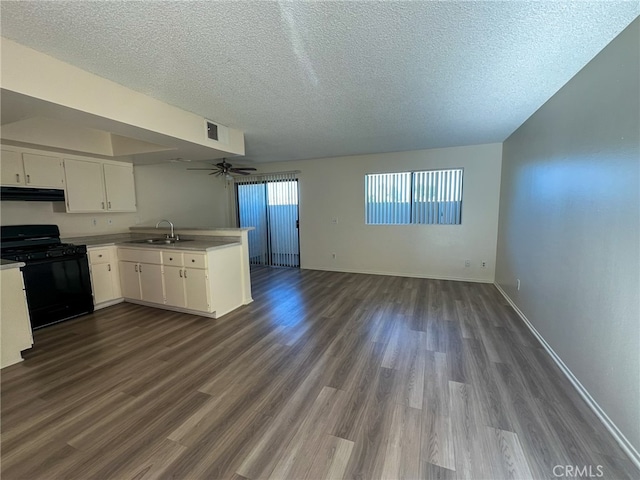 kitchen featuring dark wood-type flooring, kitchen peninsula, gas stove, and white cabinetry