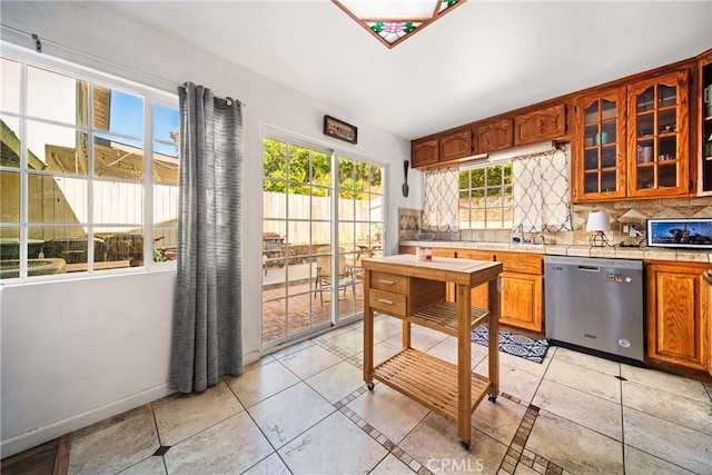 kitchen with stainless steel dishwasher, light tile patterned flooring, and tasteful backsplash