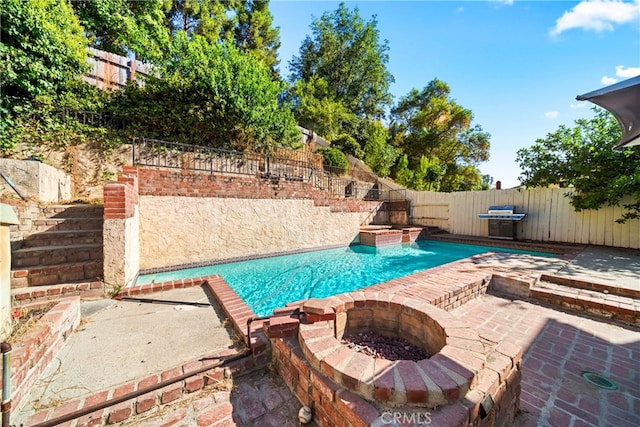 view of pool with a fire pit, a grill, a patio area, and pool water feature