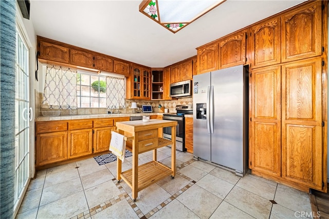 kitchen featuring decorative backsplash, stainless steel appliances, and light tile patterned floors