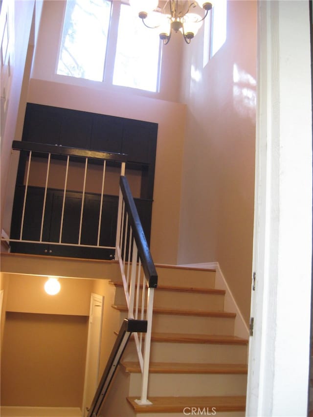 stairs featuring a high ceiling and a notable chandelier