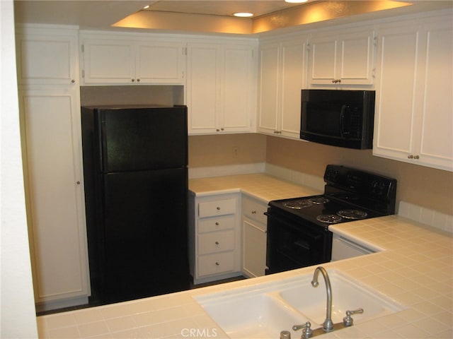 kitchen with black appliances, white cabinetry, sink, and tile countertops