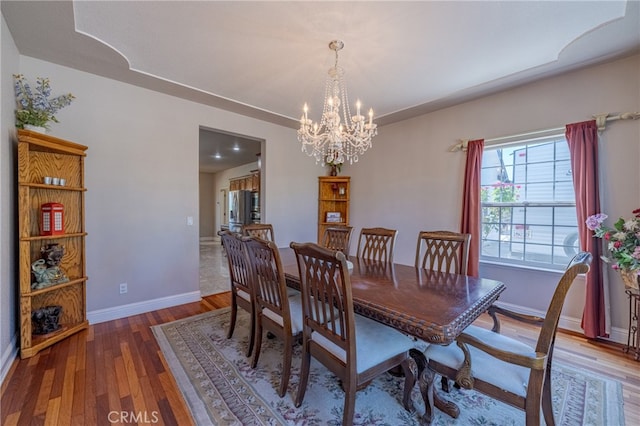 dining area with hardwood / wood-style floors and a chandelier