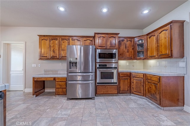 kitchen with stainless steel appliances, tile counters, and decorative backsplash