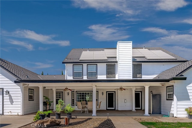 rear view of property with ceiling fan, solar panels, and a patio