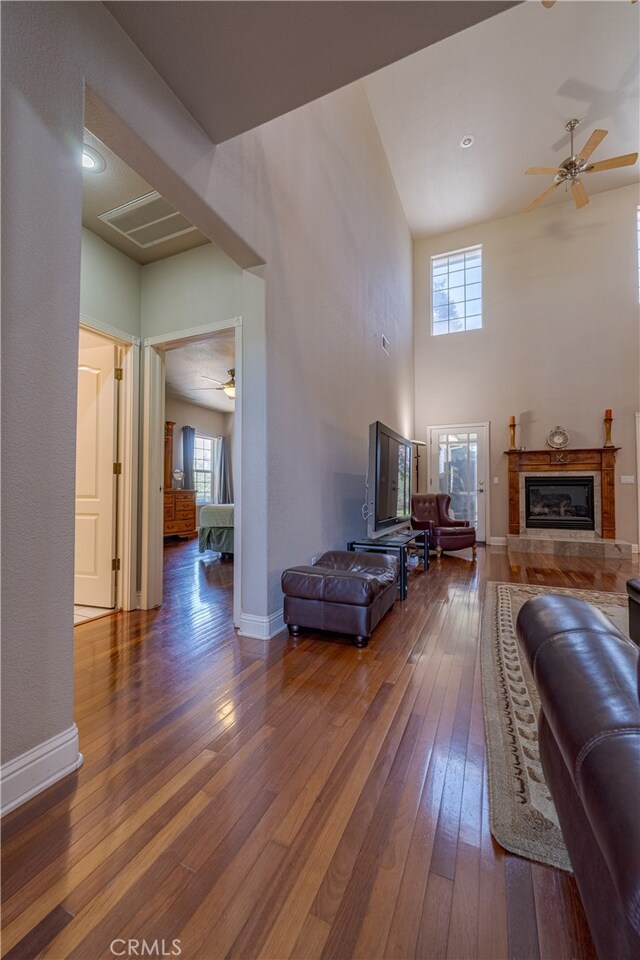 living room with ceiling fan, a wealth of natural light, dark wood-type flooring, and a tile fireplace