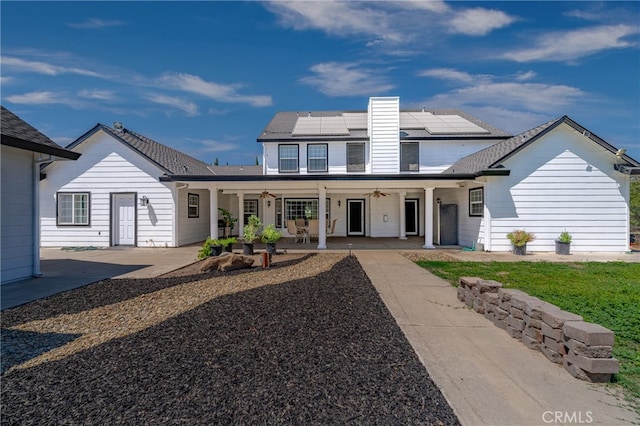 view of front of house featuring a patio area, solar panels, and ceiling fan