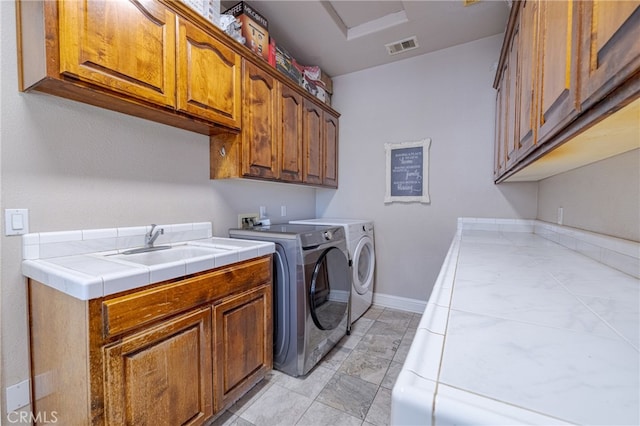 laundry area featuring washing machine and dryer, cabinets, and sink