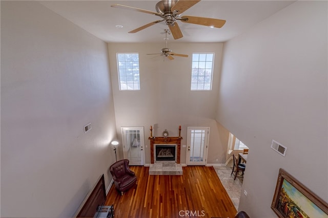 unfurnished living room featuring a tiled fireplace, hardwood / wood-style floors, and ceiling fan