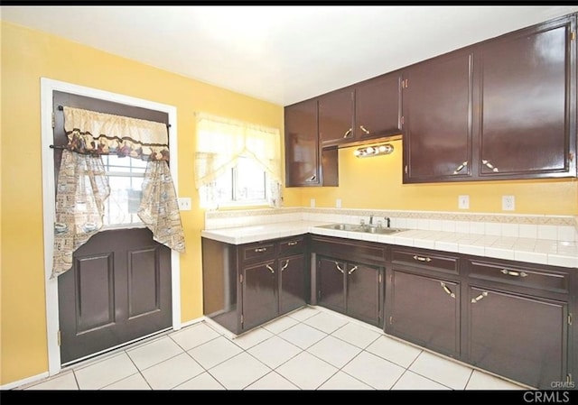 kitchen with dark brown cabinets, light tile patterned floors, and sink