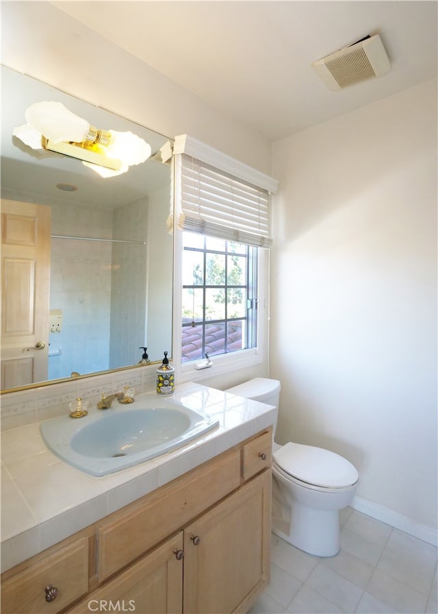 bathroom featuring a tile shower, tile patterned floors, vanity, and toilet