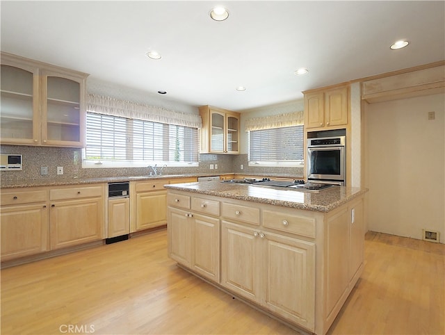 kitchen featuring tasteful backsplash, a kitchen island, light hardwood / wood-style flooring, stainless steel appliances, and light brown cabinetry