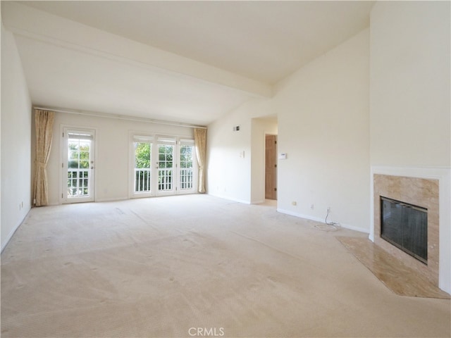 unfurnished living room with lofted ceiling with beams, light carpet, and a high end fireplace