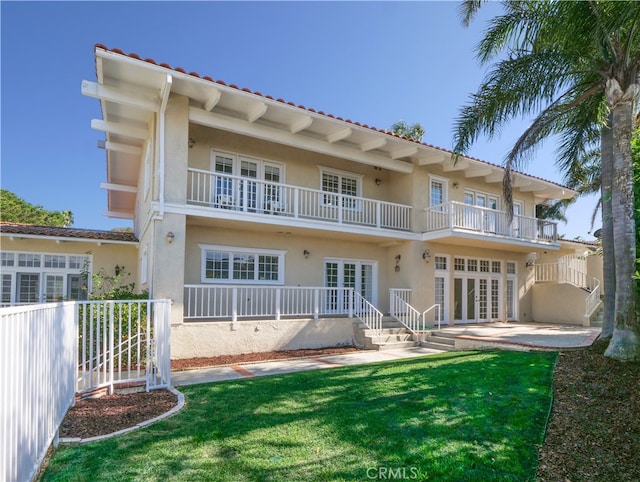 back of house with french doors, a balcony, a lawn, and a patio area