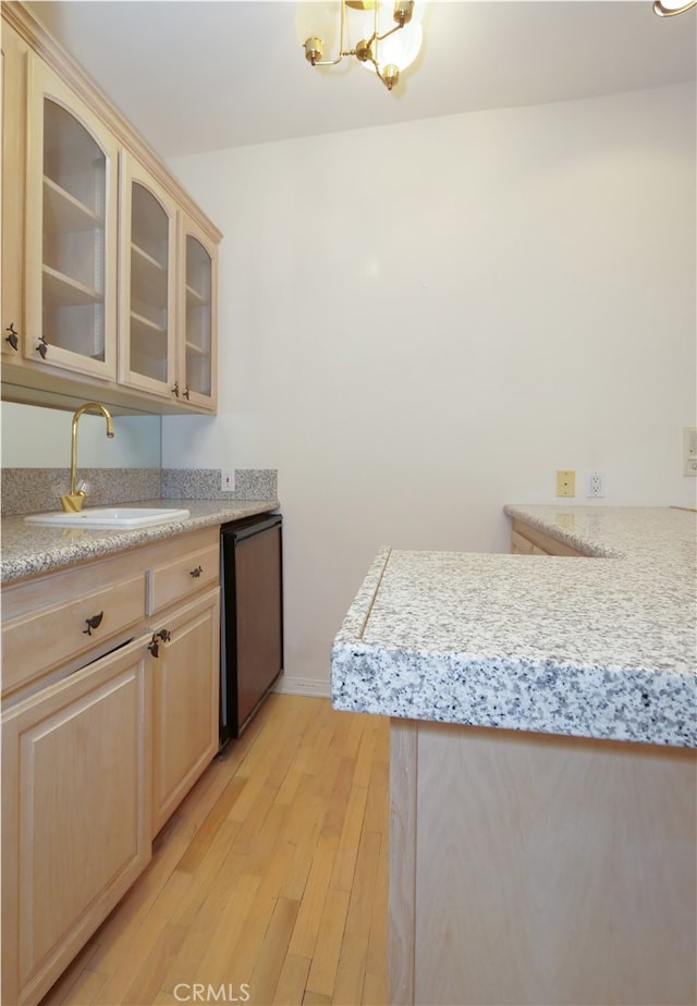 kitchen featuring light hardwood / wood-style flooring, black dishwasher, light brown cabinets, and sink