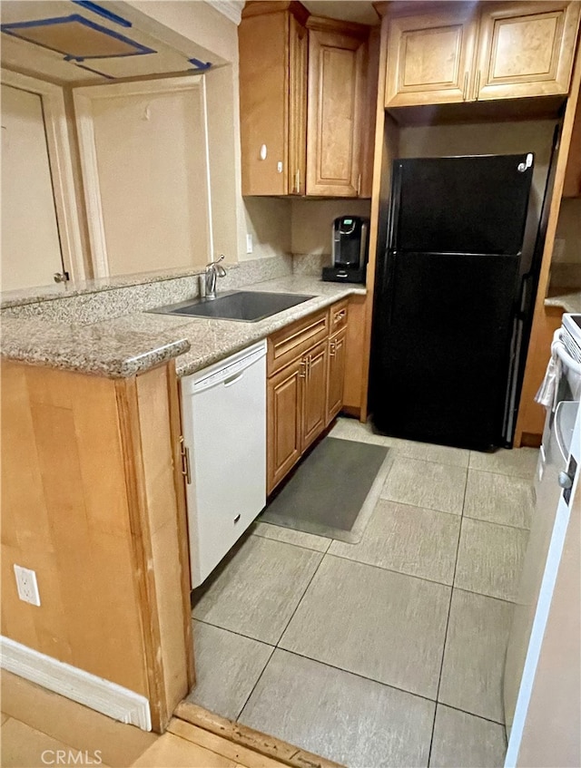 kitchen featuring sink, light tile patterned floors, light stone countertops, white dishwasher, and black refrigerator