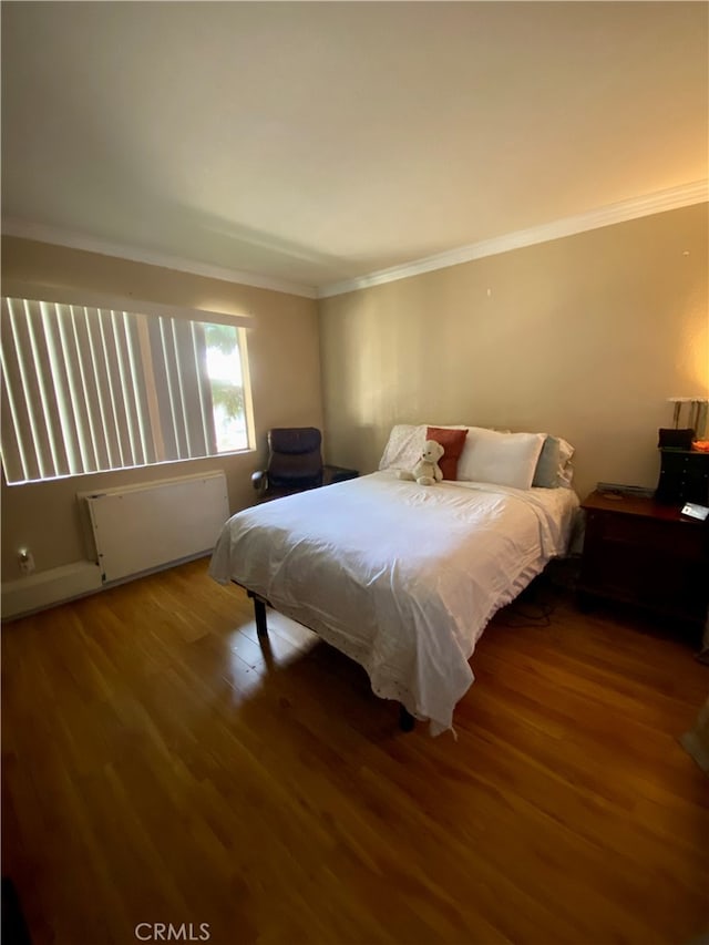 bedroom featuring crown molding, radiator, and hardwood / wood-style flooring