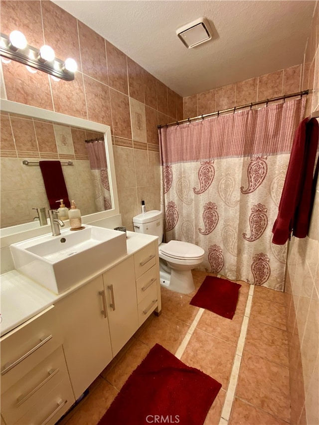 bathroom featuring a textured ceiling, tile walls, vanity, and toilet