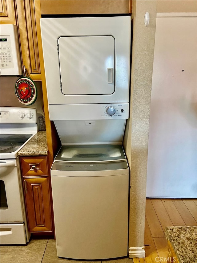 laundry room with stacked washer and clothes dryer and light hardwood / wood-style flooring