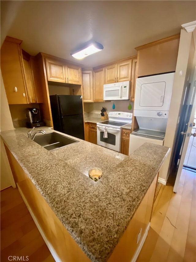 kitchen featuring stacked washing maching and dryer, white appliances, kitchen peninsula, light hardwood / wood-style flooring, and sink