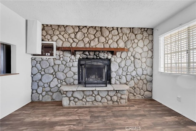 unfurnished living room with a fireplace, a textured ceiling, dark hardwood / wood-style floors, and a wall mounted AC