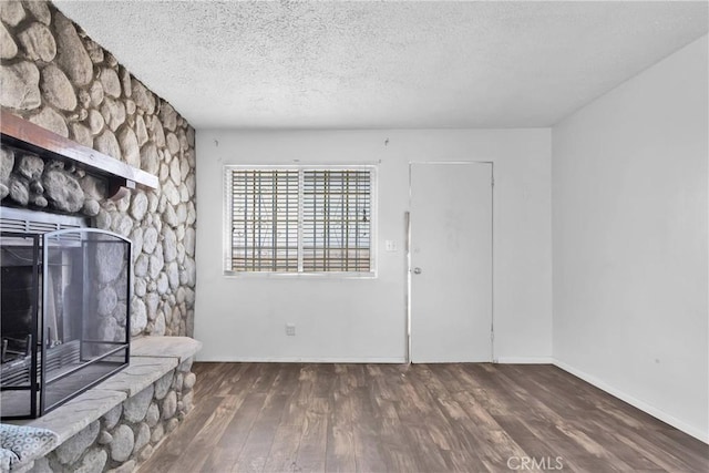 unfurnished living room with a fireplace, dark hardwood / wood-style flooring, and a textured ceiling