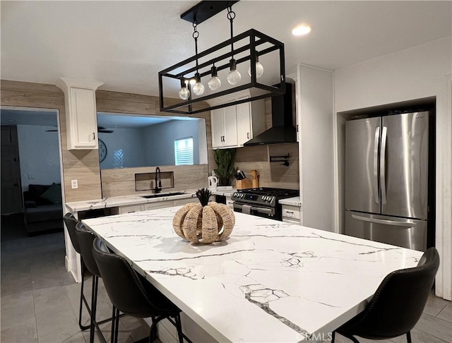 kitchen featuring backsplash, sink, wall chimney exhaust hood, appliances with stainless steel finishes, and white cabinetry