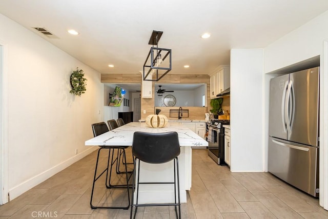 kitchen with a center island, a kitchen breakfast bar, tasteful backsplash, pendant lighting, and appliances with stainless steel finishes