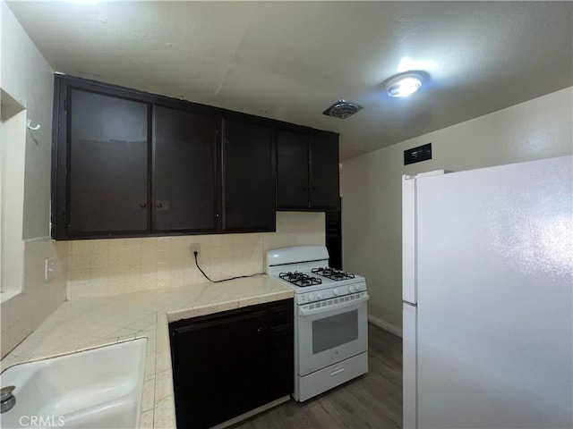 kitchen featuring white appliances, dark hardwood / wood-style floors, backsplash, and sink