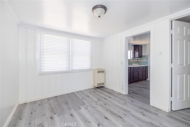 empty room featuring radiator, ornamental molding, light hardwood / wood-style flooring, and sink