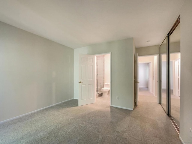 unfurnished bedroom featuring ensuite bath, light carpet, and a closet