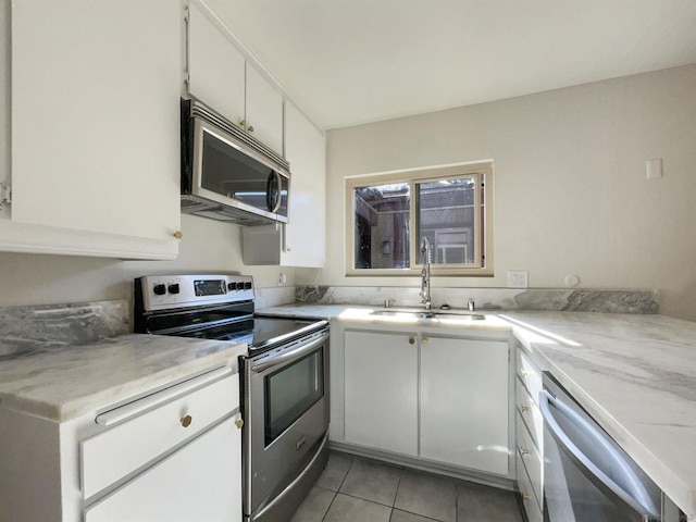 kitchen featuring white cabinets, appliances with stainless steel finishes, light tile patterned floors, and sink