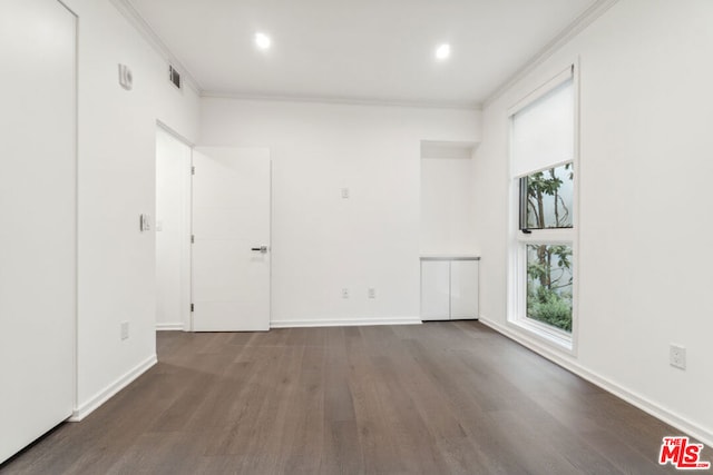 spare room with crown molding and dark wood-type flooring