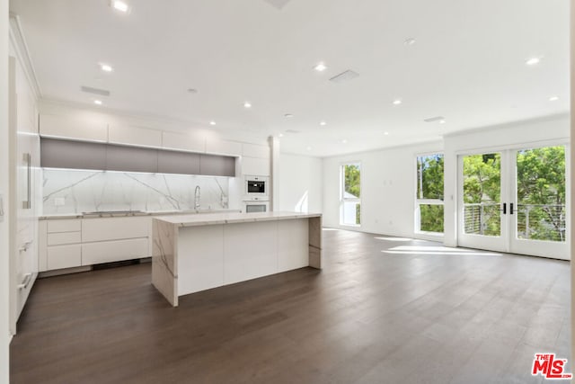 kitchen with a wealth of natural light, dark wood-type flooring, and white cabinets