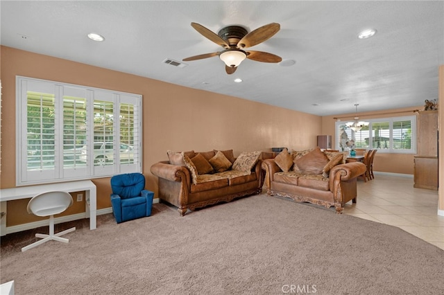 carpeted living room featuring a healthy amount of sunlight and ceiling fan with notable chandelier