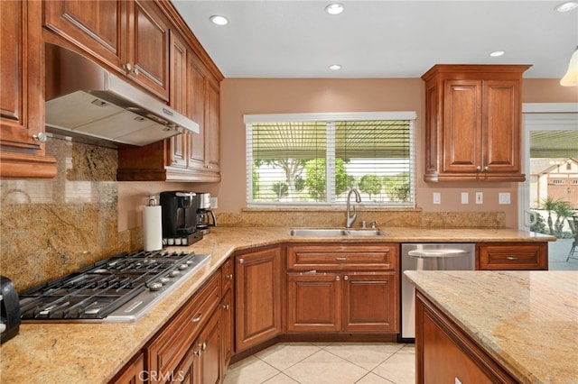 kitchen with appliances with stainless steel finishes, backsplash, light stone counters, sink, and light tile patterned flooring