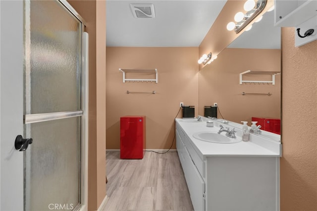 bathroom with hardwood / wood-style flooring, vanity, and a shower with shower door