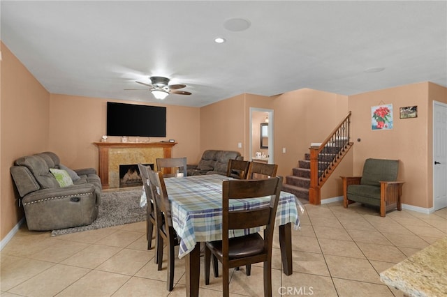 tiled dining room featuring ceiling fan and a premium fireplace